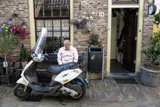847977 Portret van Henk Abels, zittend op een bankje bij een scooter, voor zijn woning in het Lange Rozendaal te Utrecht.